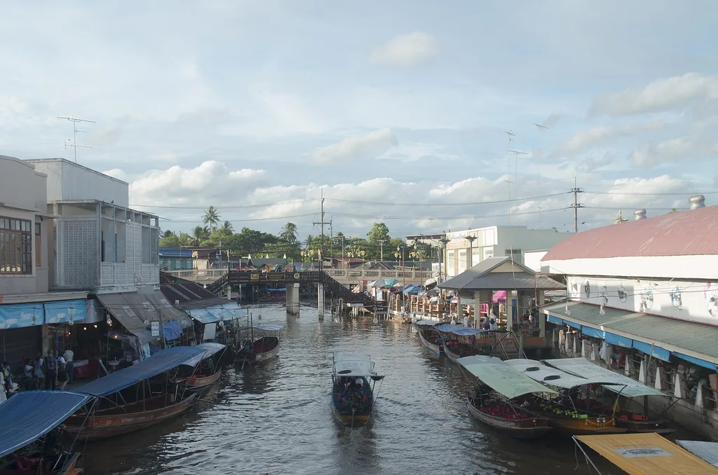 Long wooden boats moored along the canal at Amphawa floating market