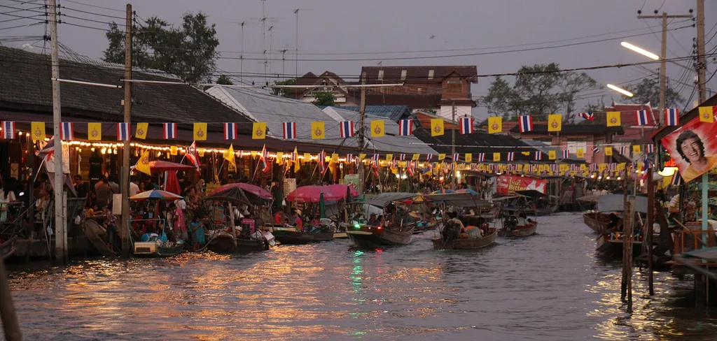 Amphawa floating market lit up along the canal after sunset