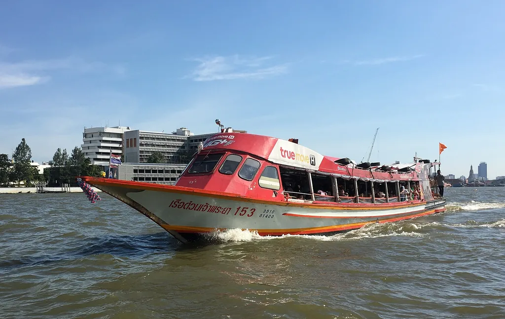 Chao Phraya Express Boat with orange flag heading upriver in Bangkok