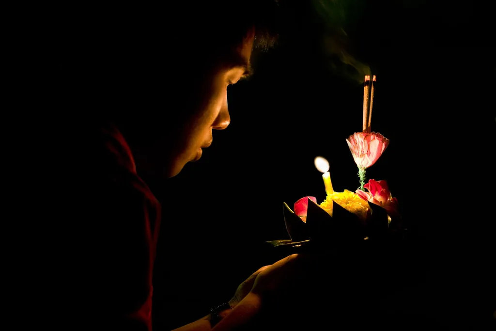 People floating candlelit banana-leaf krathongs during Loy Krathong in Bangkok