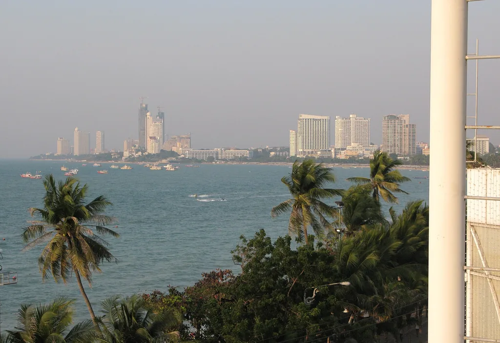 Pattaya Bay beach with deckchairs, palm trees and hotels behind